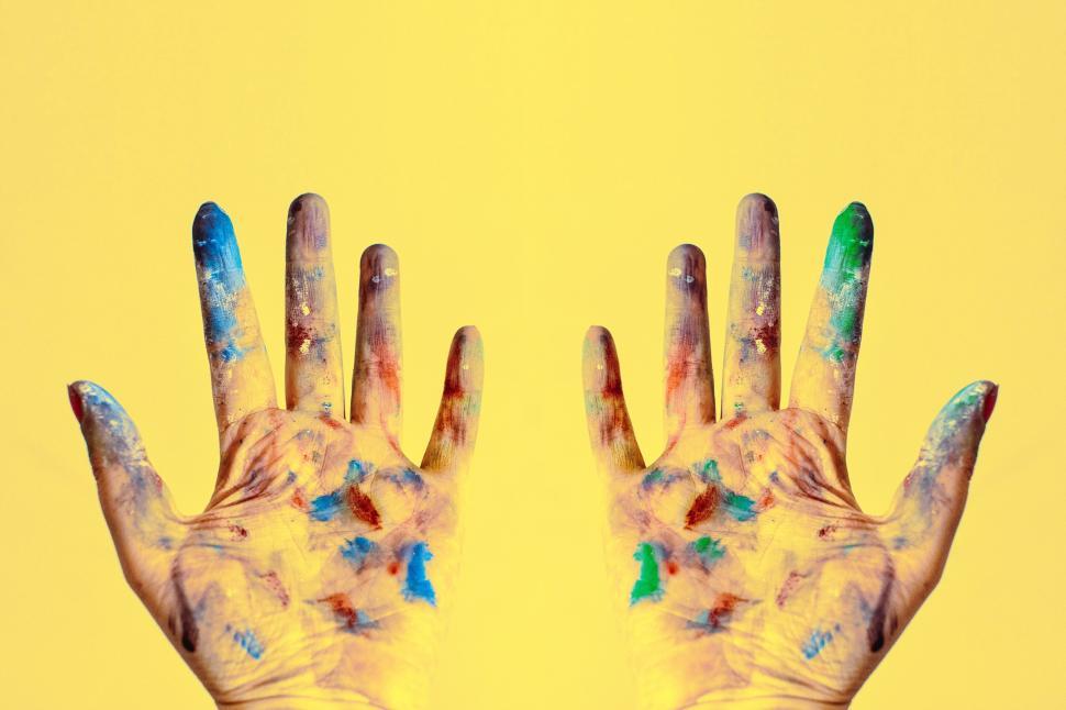 Free Image of Hands covered in vibrant paint against a bright yellow background. 