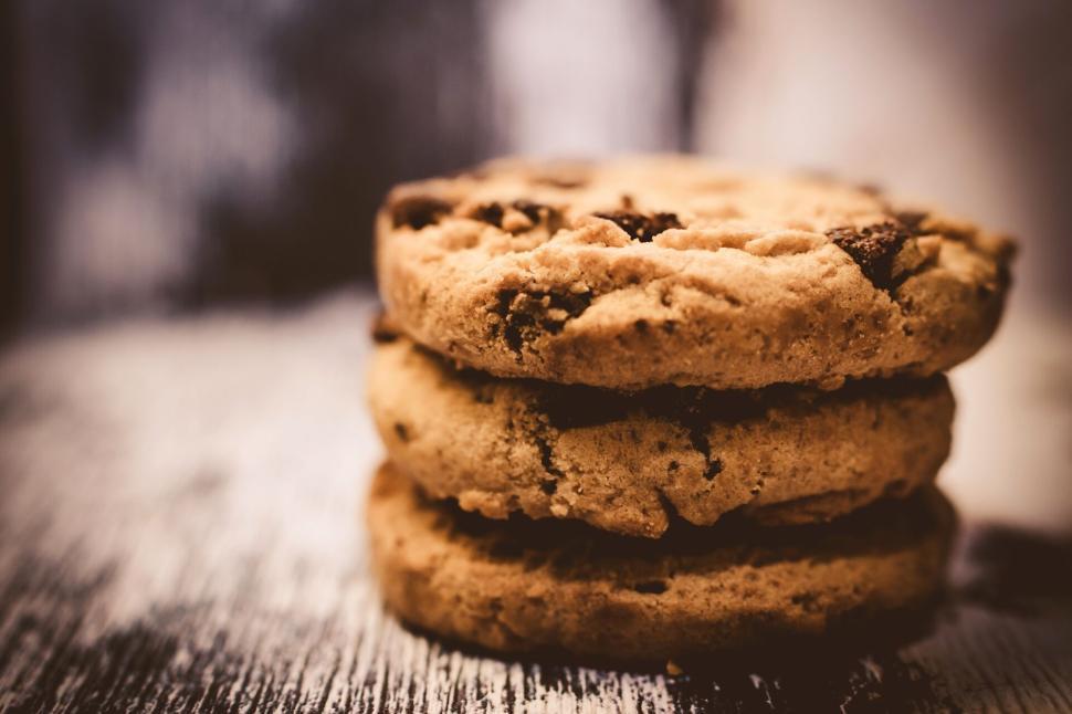 Free Image of Stacked chocolate chip cookies on a rustic wooden surface 