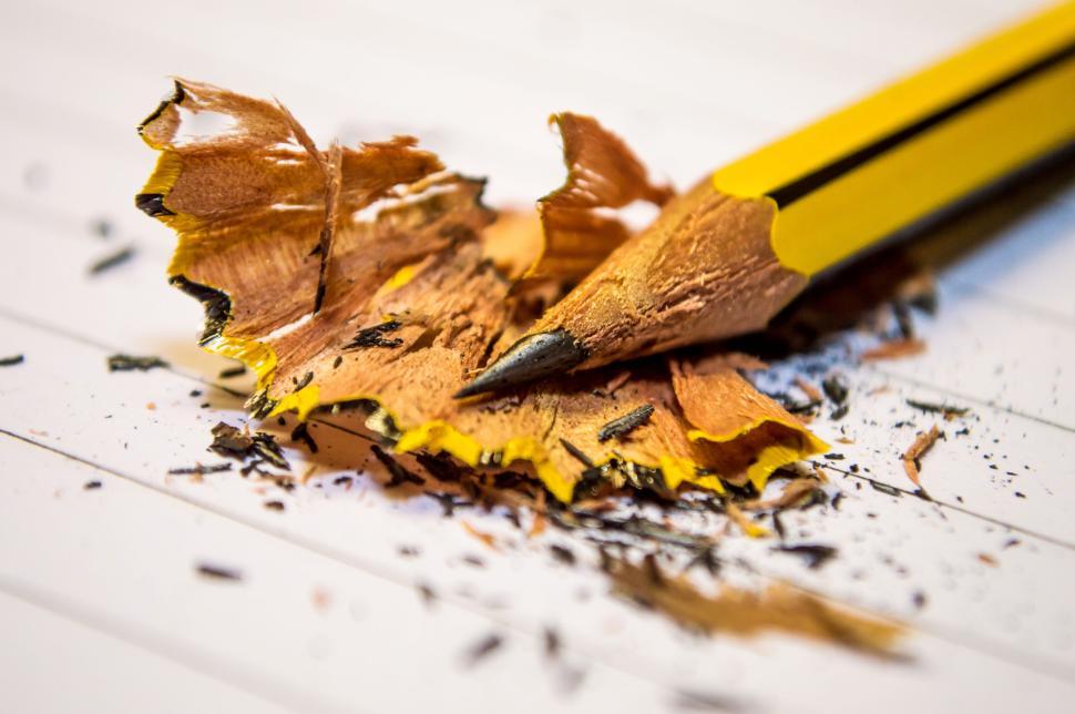 Free Image of Sharpened yellow pencil with shavings scattered on a notepad. 