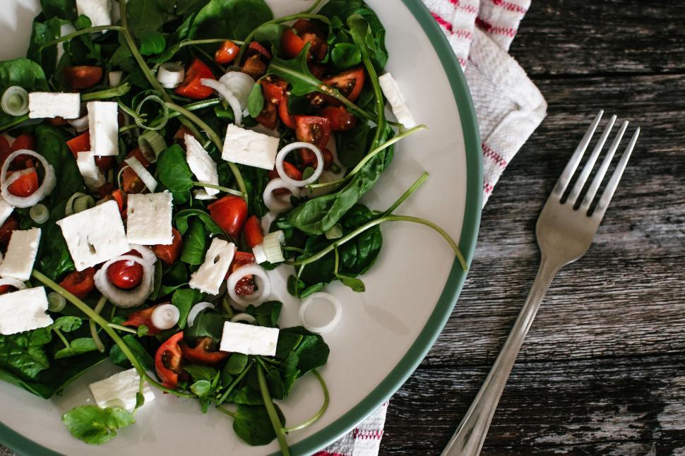 Free Image of Healthy salad with feta, cherry tomatoes, greens on wooden table. 