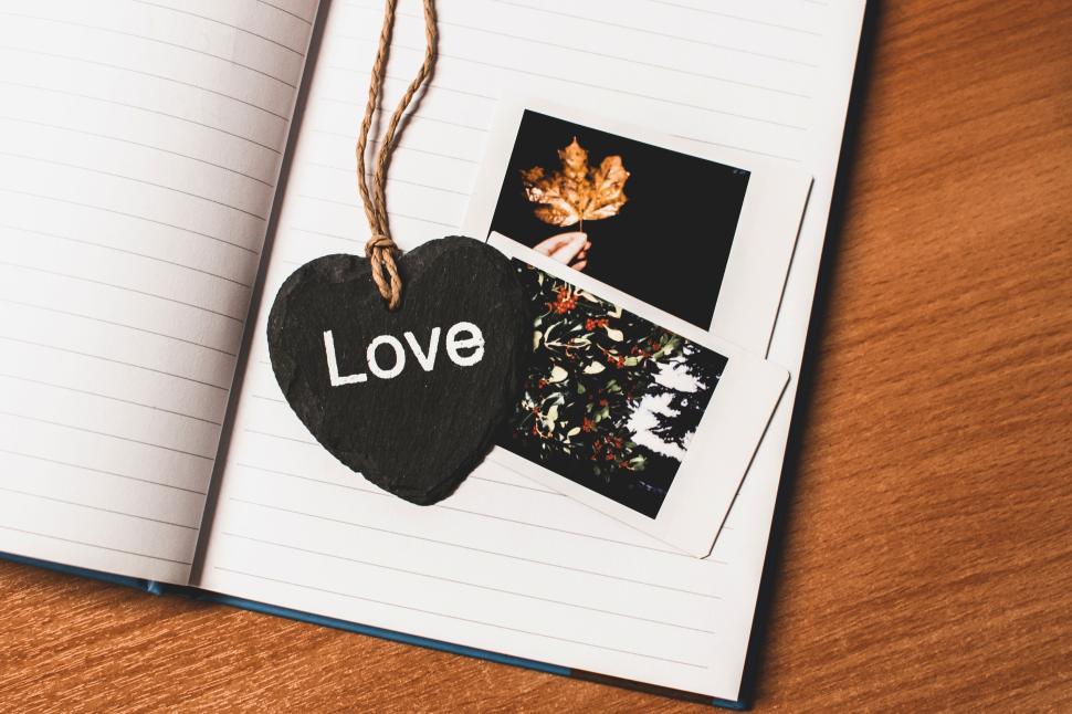 Free Image of Love-themed decoration with notebook and Polaroid images on a desk. 