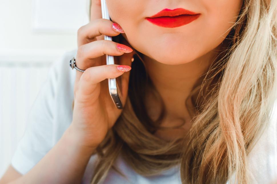 Free Image of Close-up of woman with red lipstick talking on smartphone indoors 