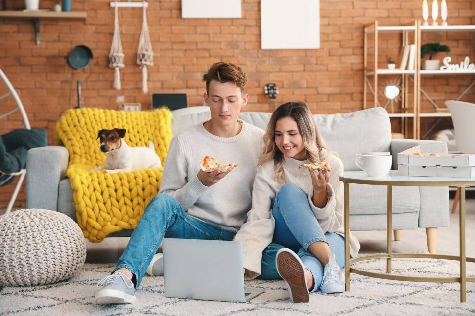 Free Image of Couple eating pizza with laptop, cozy living environment, casual. 