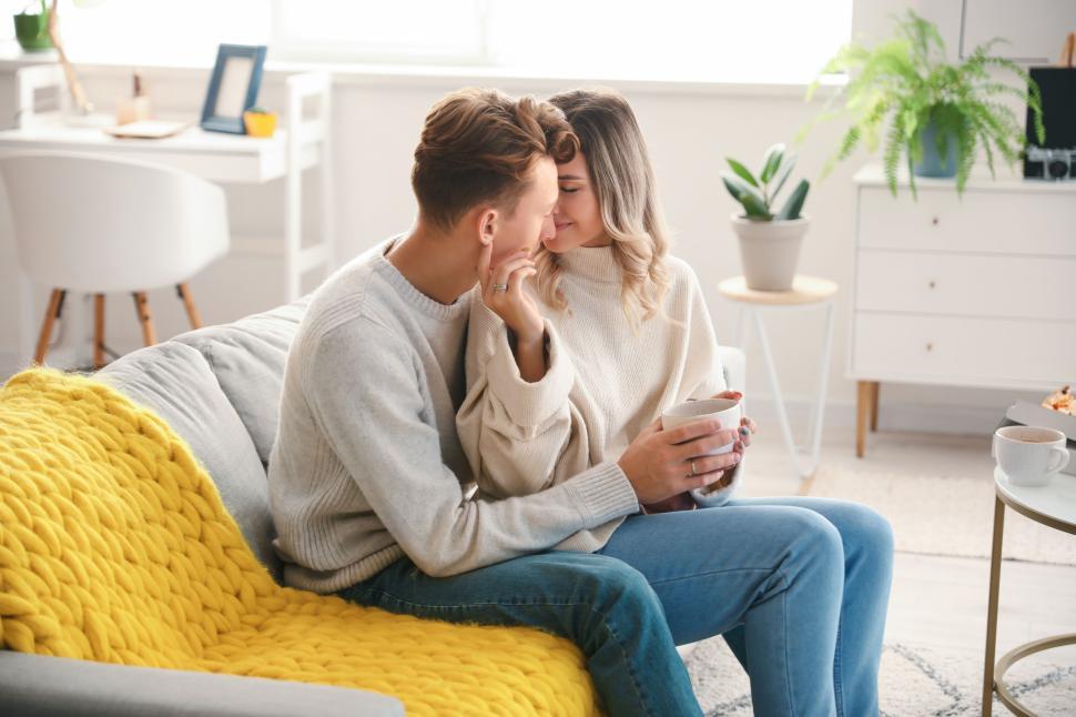 Free Image of Couple sitting on couch, sharing a moment in cozy living room 