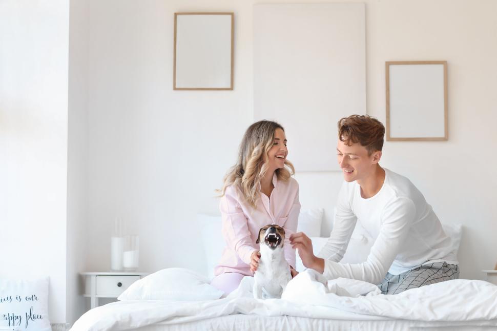 Free Image of A couple and their dog enjoying a morning in cozy bed 