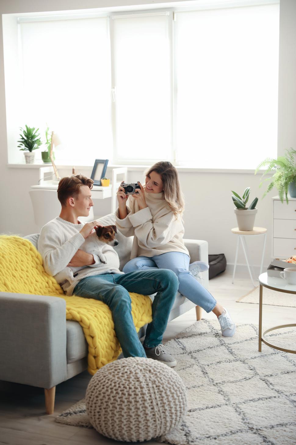 Free Image of Playful couple and playing with small dog in cozy living room. 