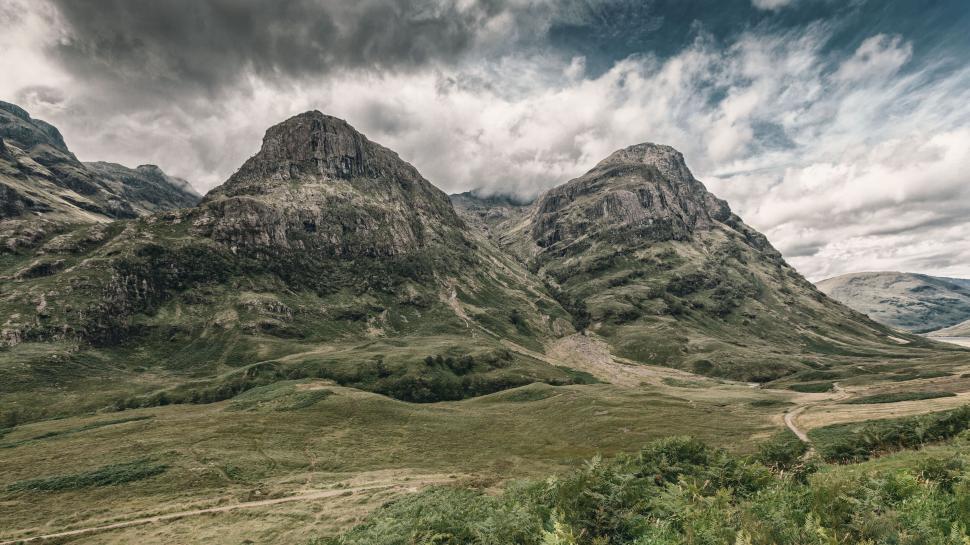 Free Image of Expansive view of green mountainous landscape under cloudy sky 