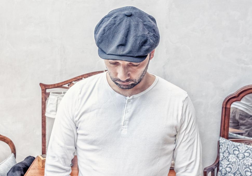 Free Image of Person in white shirt with blue cap sitting in simple setting 