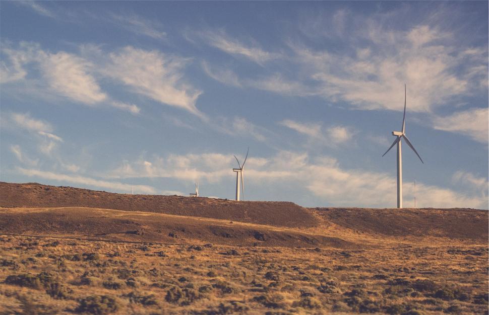 Free Image of Wind turbines on open plain under a blue sky with white clouds. 