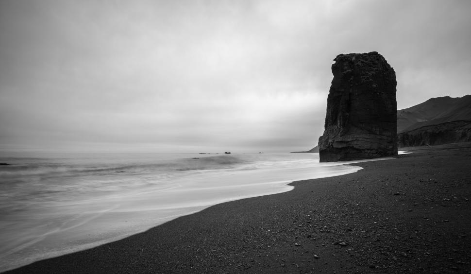 Free Image of Monochrome view of a solitary rock on a desolate beach landscape. 