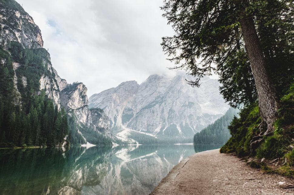 Free Image of Calm, reflective lake surrounded by mountains and dense forests 