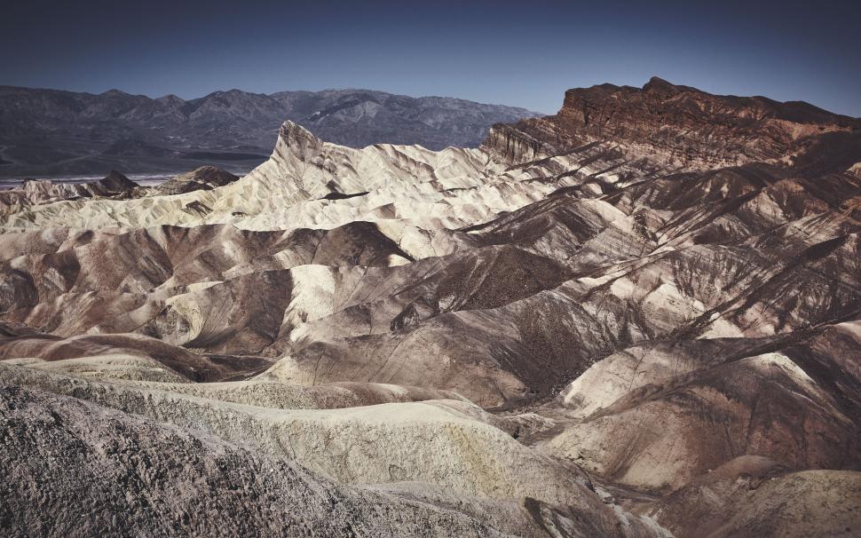 Free Image of Desert landscape view with rugged terrain and distant mountains sky. 