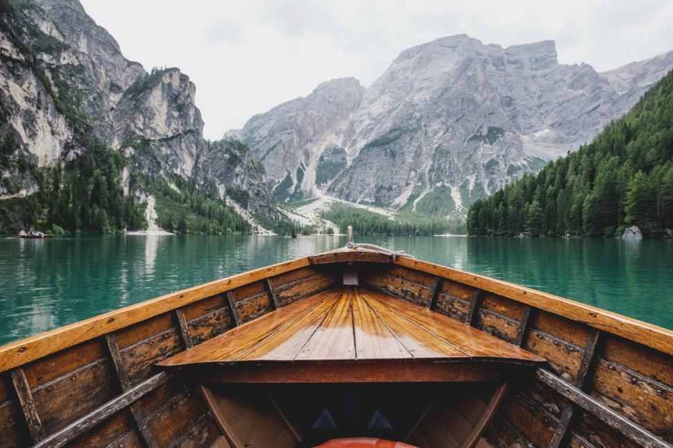 Free Image of A wooden boat on a serene mountain lake surrounded by high peaks. 