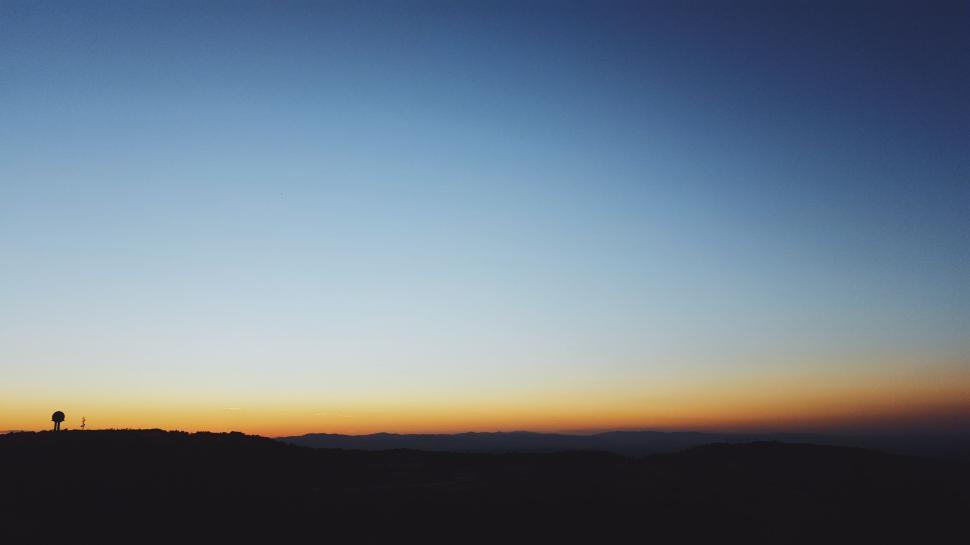 Free Image of Silhouetted landscape with a glowing twilight sky. 