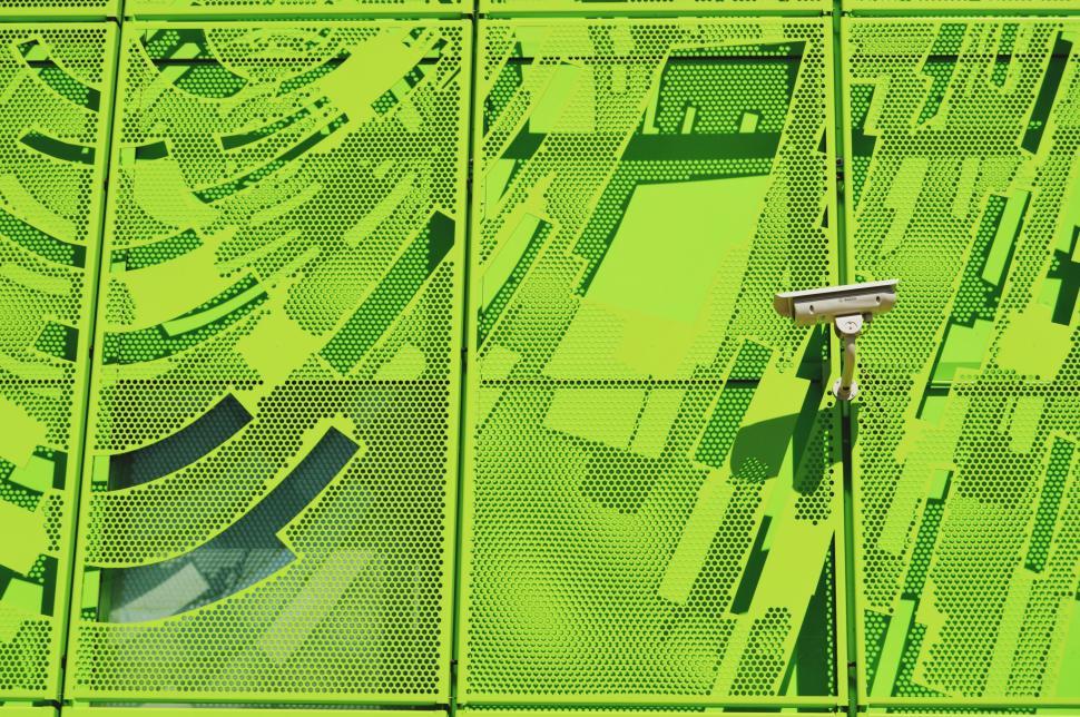 Free Image of Bright green perforated wall with security camera installation. 