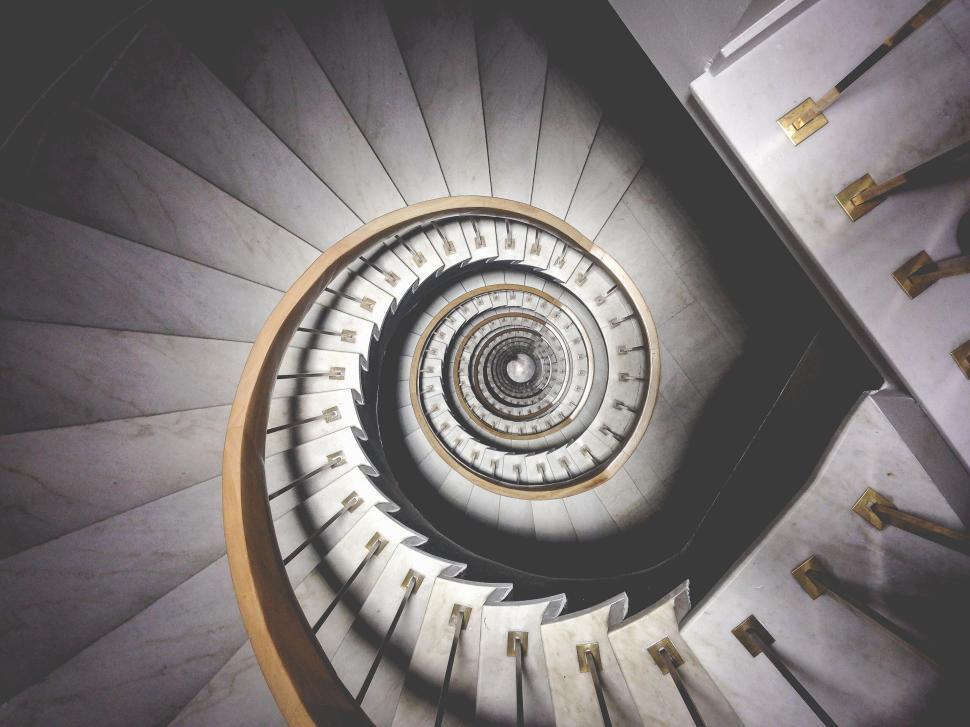Free Image of Intricate spiral staircase with marble steps and ornate railing 