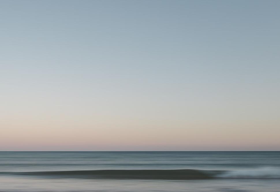 Free Image of Serene twilight over calm ocean waves with colorful sky above 
