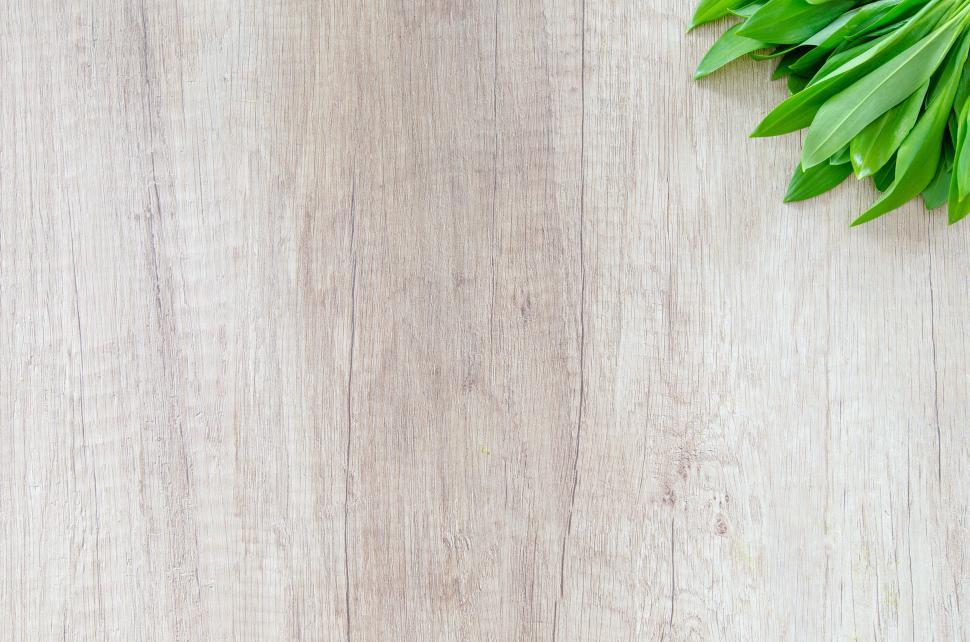 Free Image of Wooden table surface with green leaves at the top right corner 
