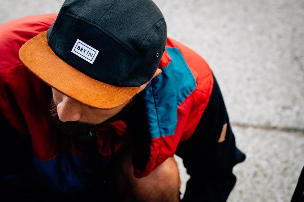 Free Image of Person in colorful jacket and cap crouching on pavement outdoors 