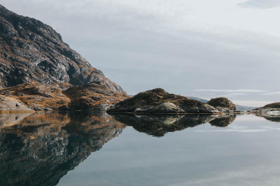 Free Image of Serene lake reflecting rocky mountains and a clear sky 