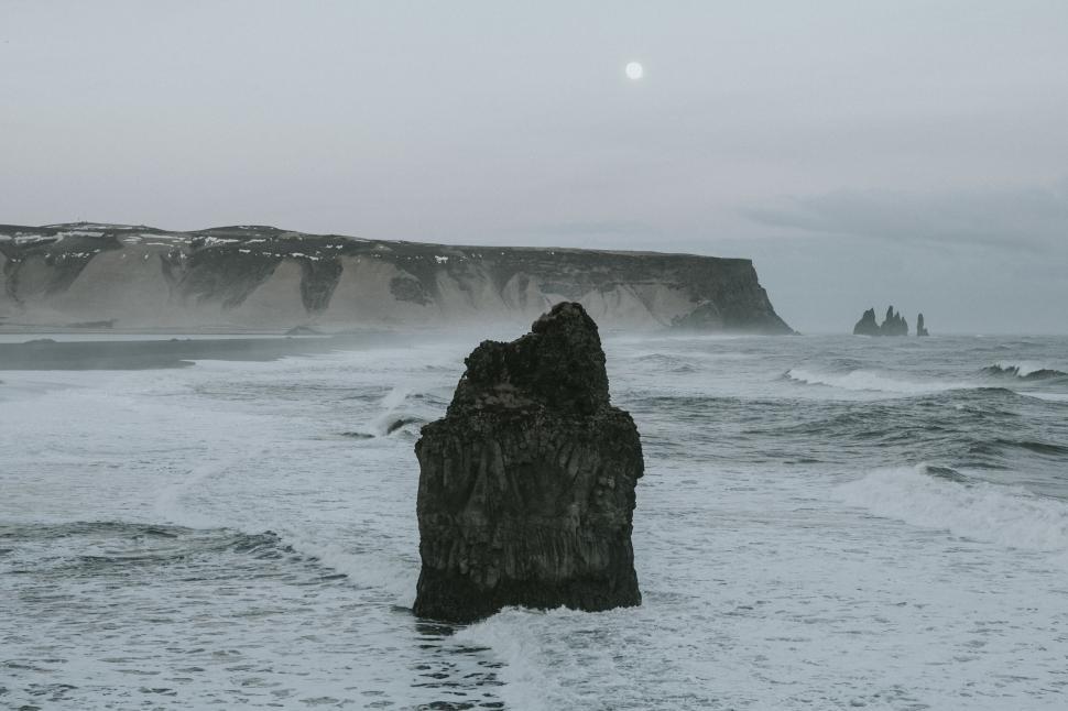 Free Image of Dramatic coastal rock formations under a cloudy sky at sunset 