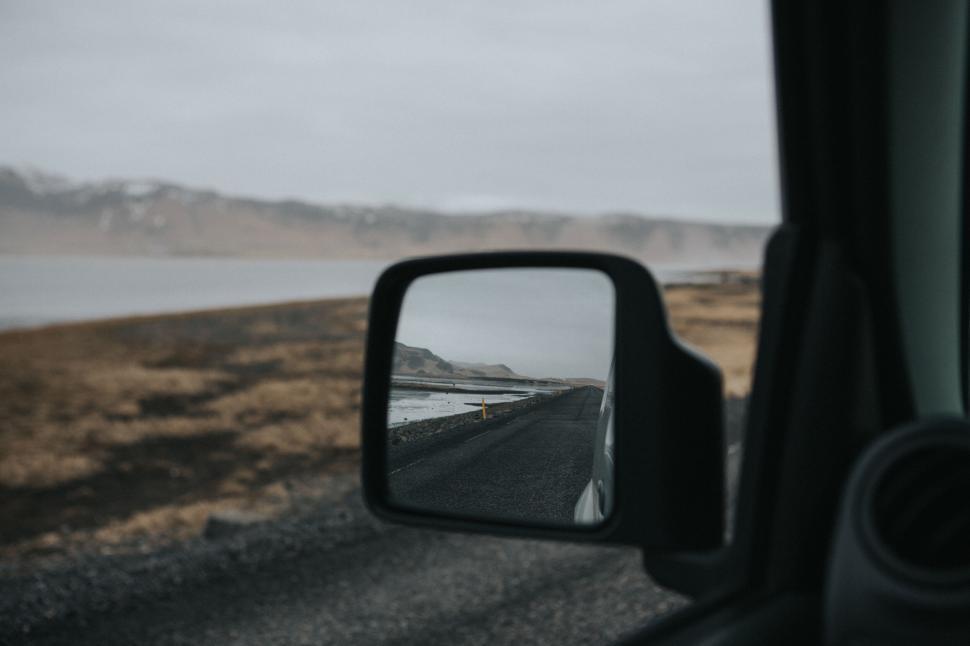 Free Image of Road through barren landscape reflected in side view car mirror. 