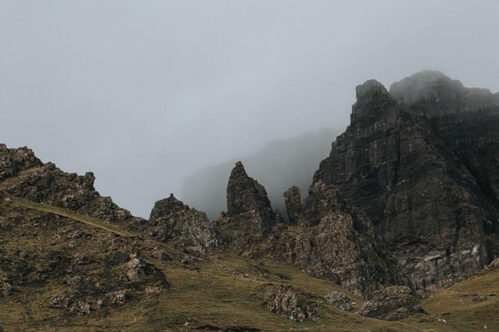Free Image of Misty mountain range with dramatic rocky peaks under overcast sky. 