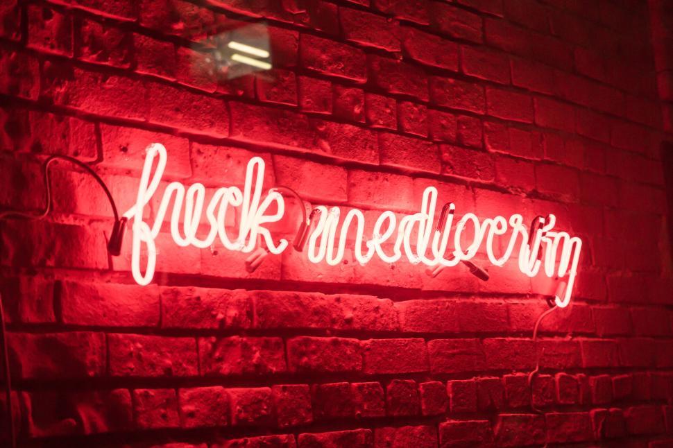 Free Image of Red neon sign displaying motivational phrase on brick wall 