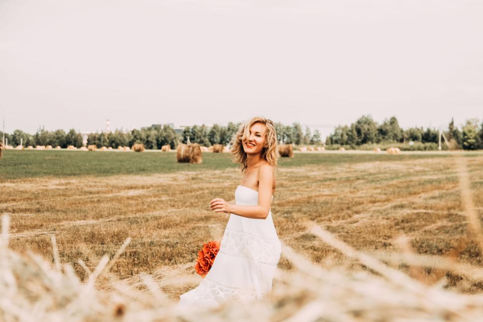 Free Image of Smiling woman in a white dress enjoying a field day 