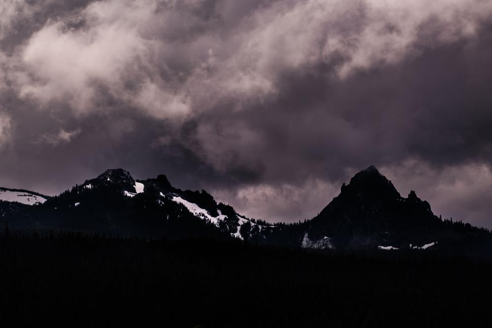 Free Image of Mountain peaks under dramatic cloudy sky at dusk. 