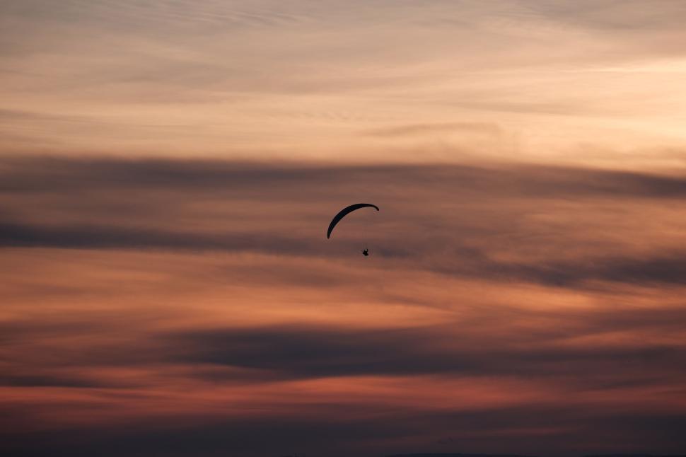 Free Image of Silhouette of a paraglider against a colorful sunset sky 