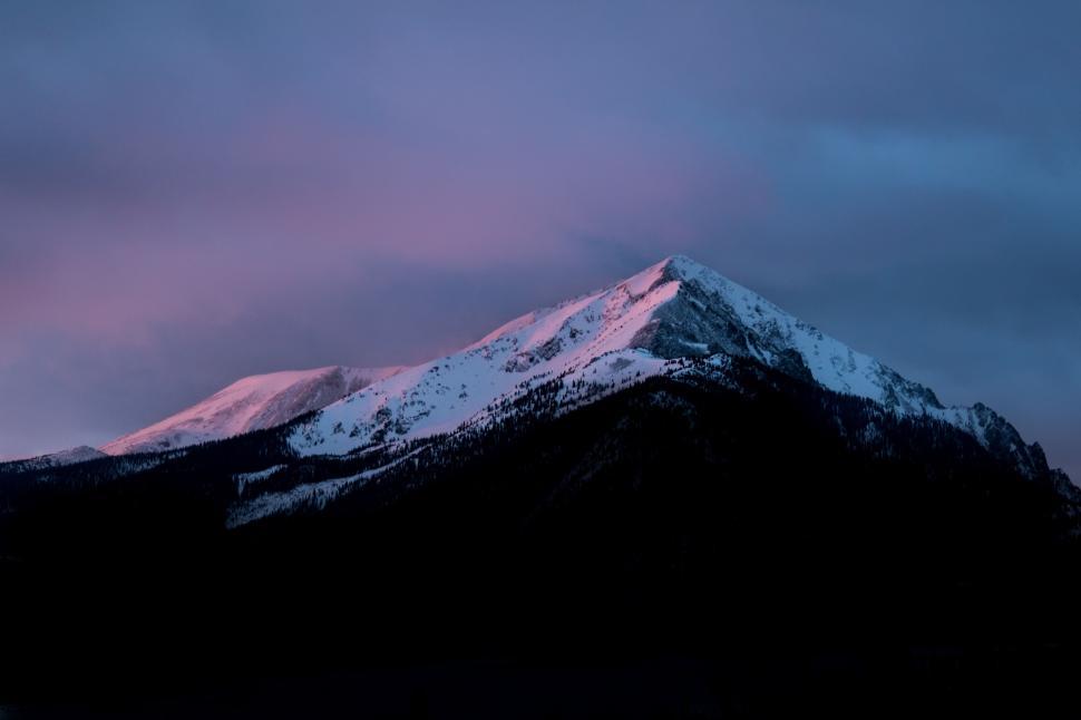 Free Image of Sunset over snowy mountain peak with twilight hues 