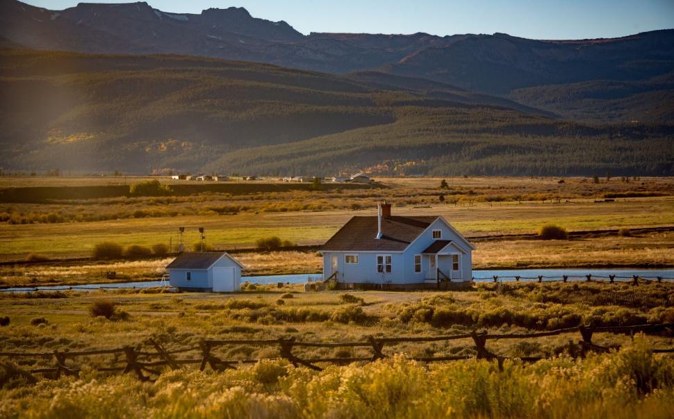 Free Image of House in open field with mountains in the background. 