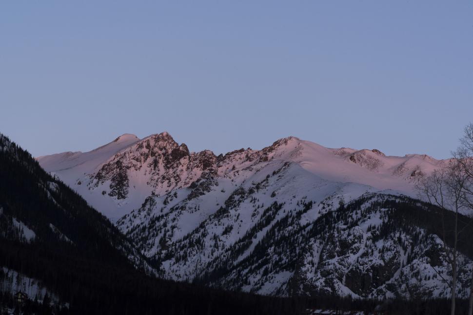 Free Image of Sunset hue on snow-covered mountain landscape 
