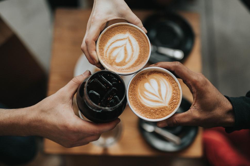 Free Image of People toasting with hot lattes and iced coffee cups 