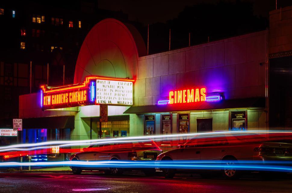Free Image of Neon-lit cinema with moving vehicle light trails outside 