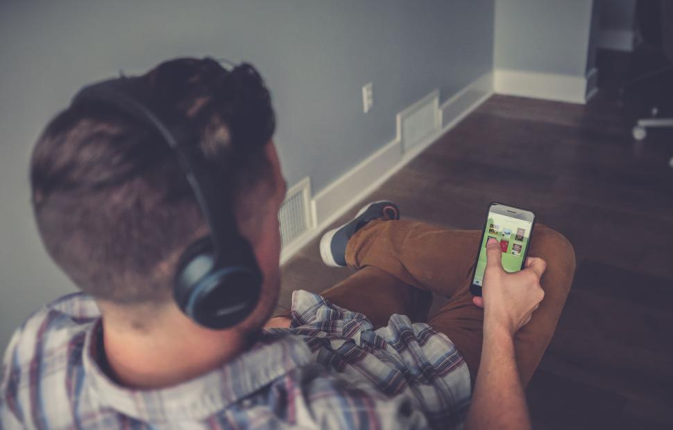 Free Image of Man sitting on floor using smartphone and headphones. 