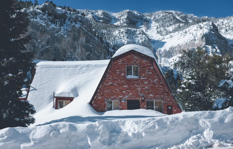 Free Image of Red brick house blanketed with fresh snow amid mountains 