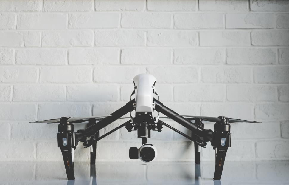 Free Image of Advanced white and black drone against white brick wall 