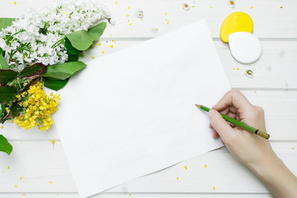 Free Image of Writing on blank paper beside flowers and art supplies 