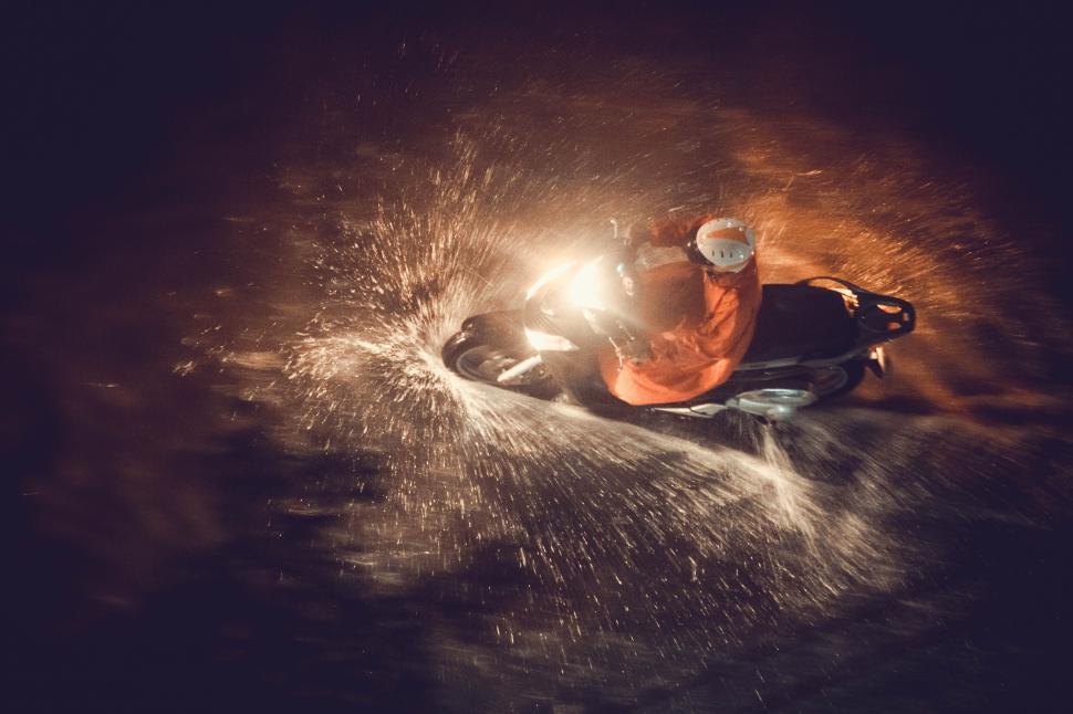 Free Image of Motorcyclist rides through water splashes at night. 