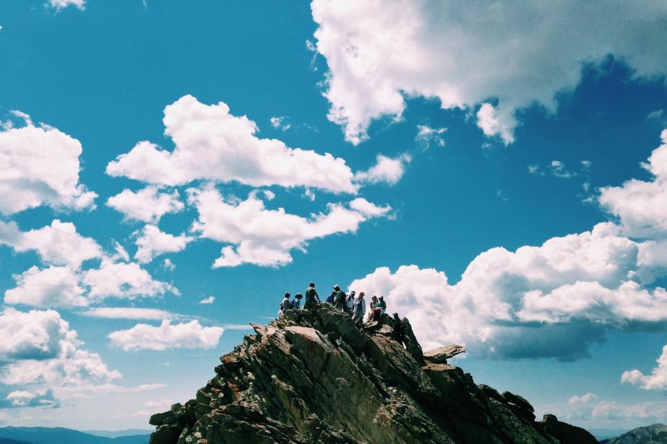 Free Image of Group of people standing on rocky mountain peak 