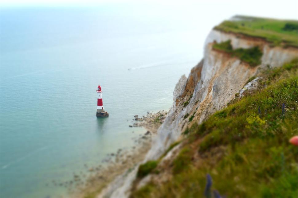 Free Image of Lighthouse at edge of cliff overlooking ocean water 