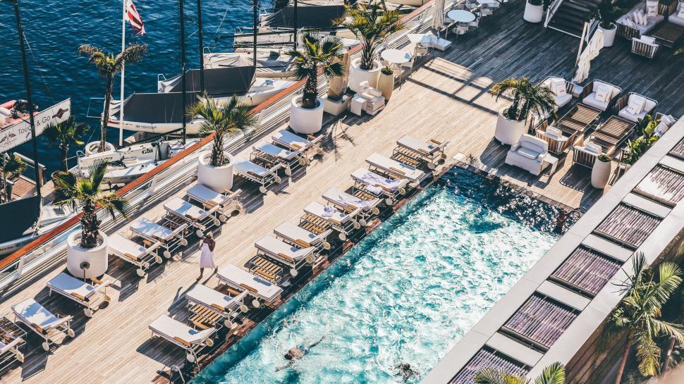 Free Image of Luxurious poolside with loungers beside a scenic marina 