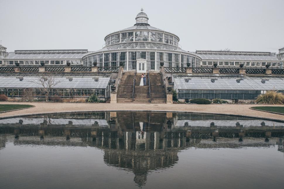 Free Image of Large glass greenhouse in symmetrical design reflected water. 