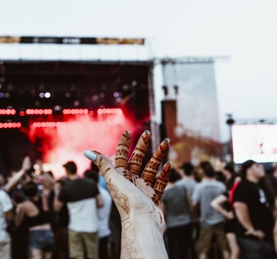 Free Image of Henna-tattooed hand raised in front of a concert stage 