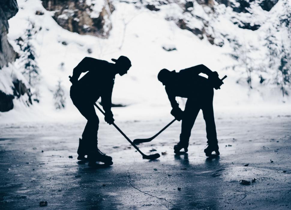 Free Image of Two people playing hockey on an icy outdoor surface 
