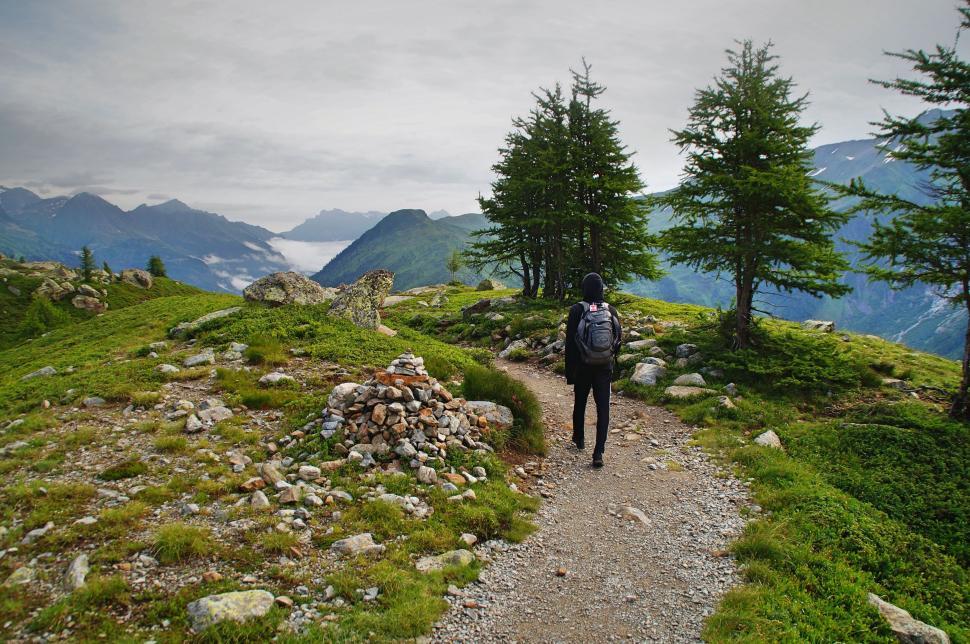 Free Image of Hiker walking on trail amidst green mountains scenery. 