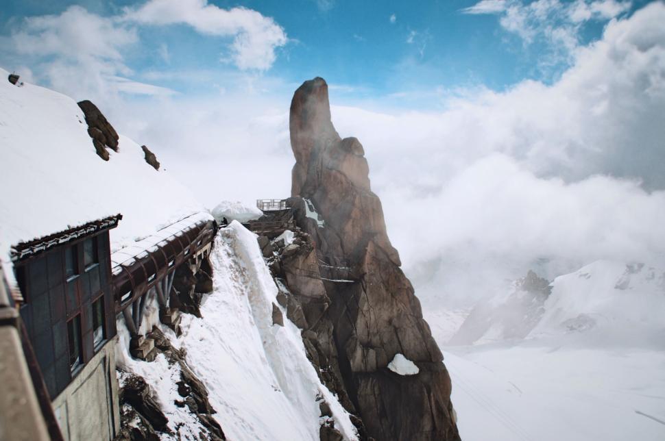Free Image of Rocky snowy peak with clouds and observation platform 