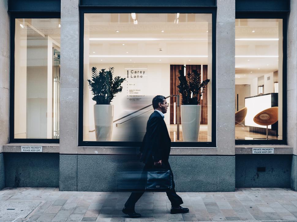 Free Image of Man walking briskly in front of an office building 